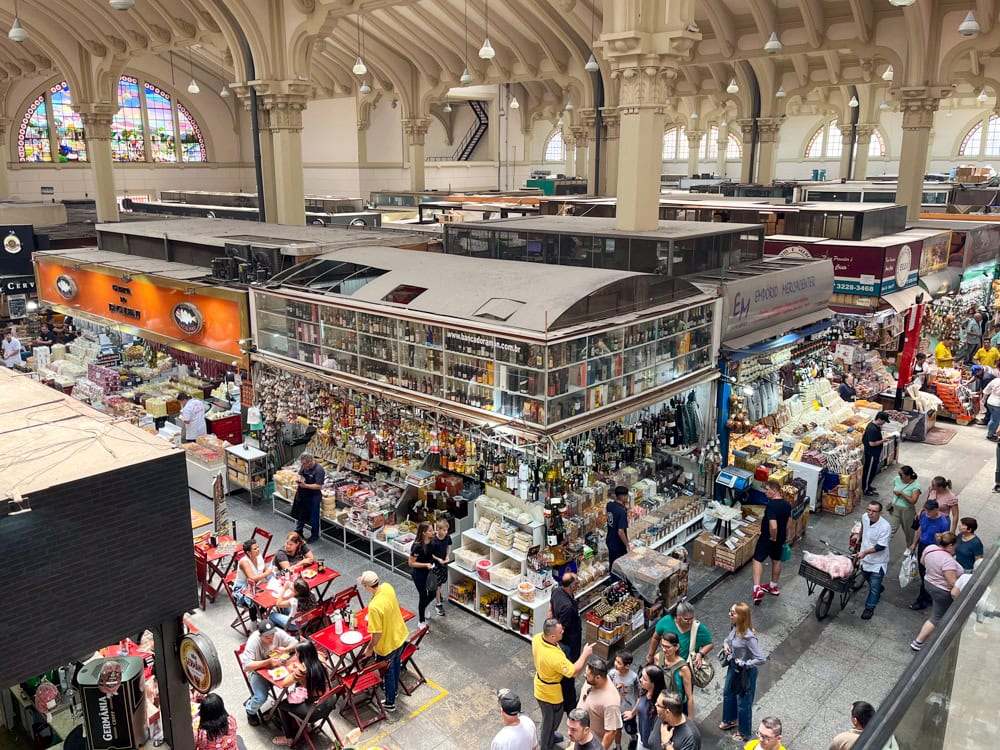 People dining and walking between the various market stalls of the bustling Municipal Market of Sao Paulo. 