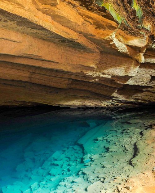 A cave with limestone walls and a pond with clear blue water at the Pratinha ecotourism farm