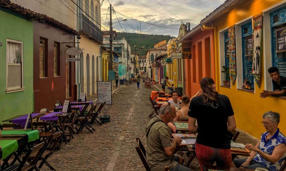 A cobblestone street lined with colorful houses and sidewalk cafes in Lencois.