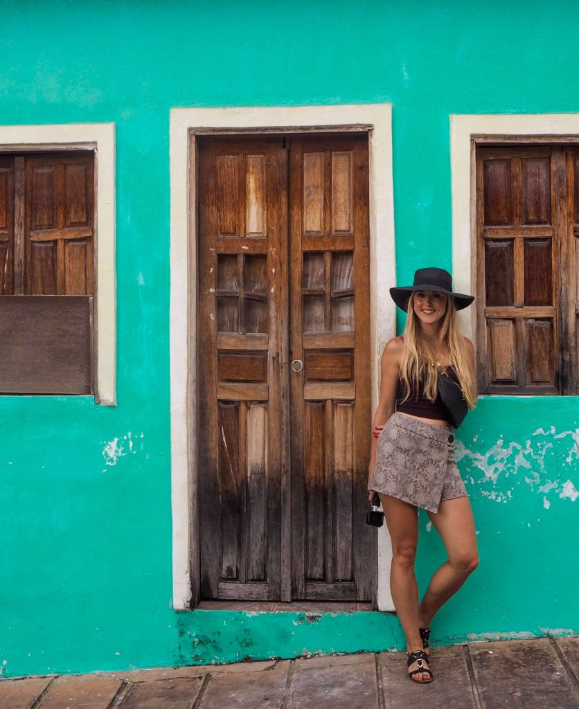 me posing with a small house with vibrant turquoise walls in Lencois