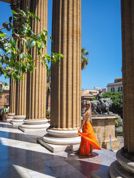 Me standing between huge columns inspired by ancient Greek temples at the entrance of Teatro Massimo.