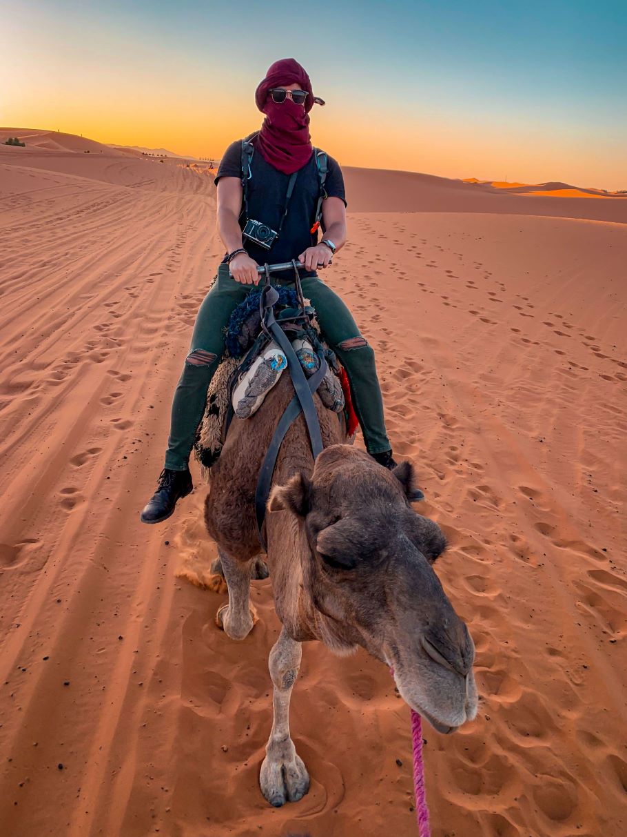 Camel riding at sunset at Erg Chebbi sand dunes in the Sahara desert, Morocco