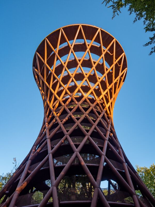 The hourglass-shaped Forest Tower in the evening sun with blue sky in the background.