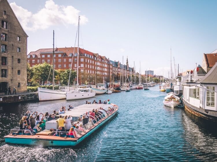 Tourists on a Copenhagen canal tour boat sailing through the Christianshavn neighborhood, one of the best Copenhagen bucket list activities