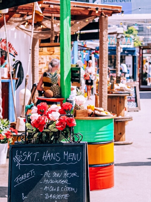 a row of colorful street food stalls on a sunny day at Reffen food market, Copenhagen