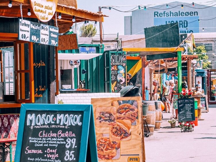 a row of colorful food stalls selling dishes from all over the world at Reffen food market