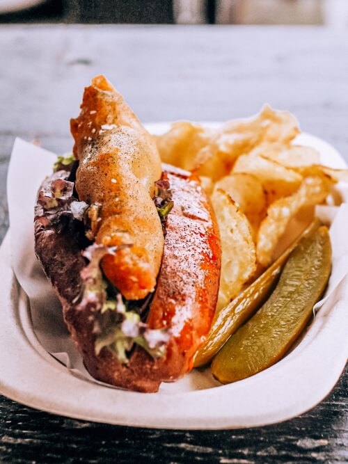 A sandwich roll with fried fish served with crisps at Broens Gadekokken street food market