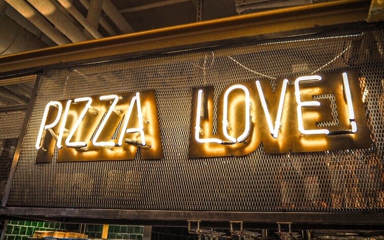 A neon sign stating "Pizza Love" in Tivoli Food Hall, one of the best markets for street food in Copenhagen