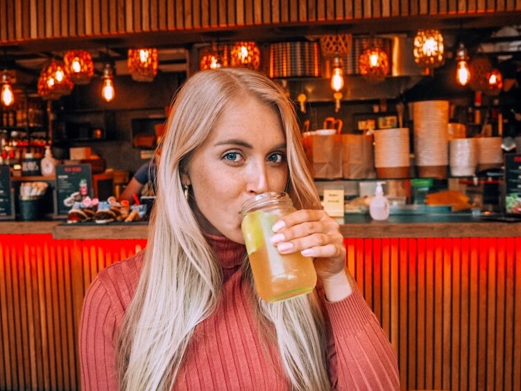 a woman sipping homemade ginger lemonade at Tivoli Food Hall, one of the best spots for street food in Copenhagen, Denmark