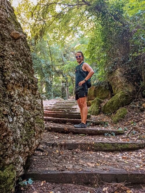 My boyfriend standing on a hiking trail consisting of wooden steps leading to the Adrachti rock in Meteora