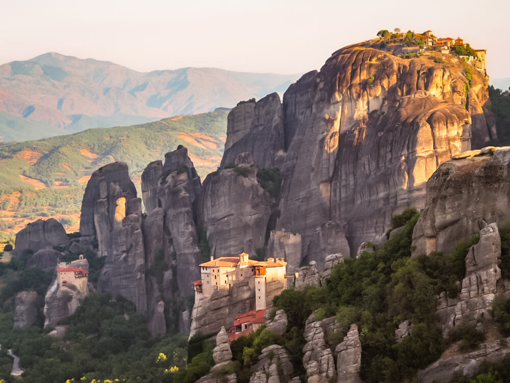 A view of three monasteries perched on top of narrow rock columns in Meteora, Greece.