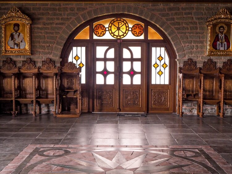 Colorful windows, grey brick walls and tiled floors of Varlaam monastery in Meteora, Greece