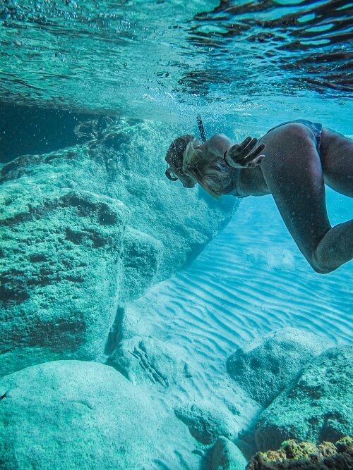 underwater shot of me snorkeling in the aquamarine waters at Kleftiko Beach, one of the best things to do in Milos, Greece