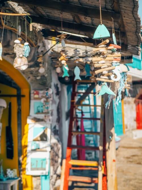 Hand-made wooden decorations hanging from a roof at a souvenir shop in Klima in Milos, Greece