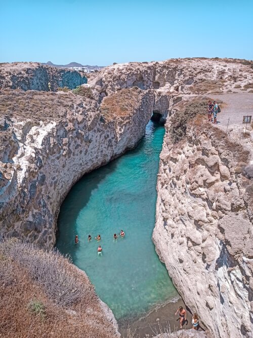 A narrow inlet of emerald water surrounded by beige cliffs at Papafragas Beach, one of the most unique places to visit in Milos