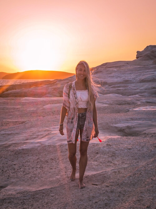 Me walking on the rocky moon-like surface of Sarakiniko beach with the rising sun behind me