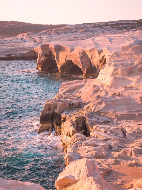 Dramatic white cliffs rising out of the sea at Sarakiniko Beach on the coast of Milos, Greece