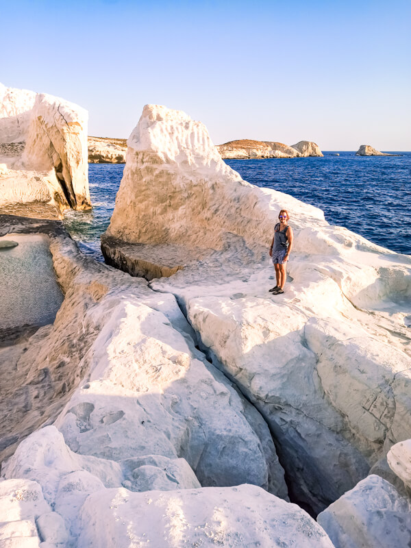 My husband standing on the white cliffs full of crevices and volcanic rock formations at Sarakiniko Beach.
