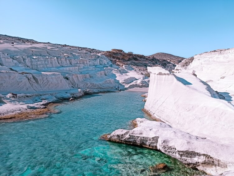 A small cove with emerald water surrounded by the white volcanic landscape of Sarakiniko, one of the most iconic beaches in Milos