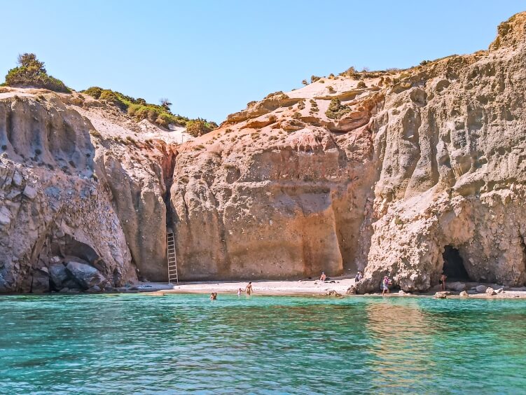 The tiny cove of Tsigrado Beach with clear turquoise water and vertical cliffs around it, one of the most unique swimming spots in Milos