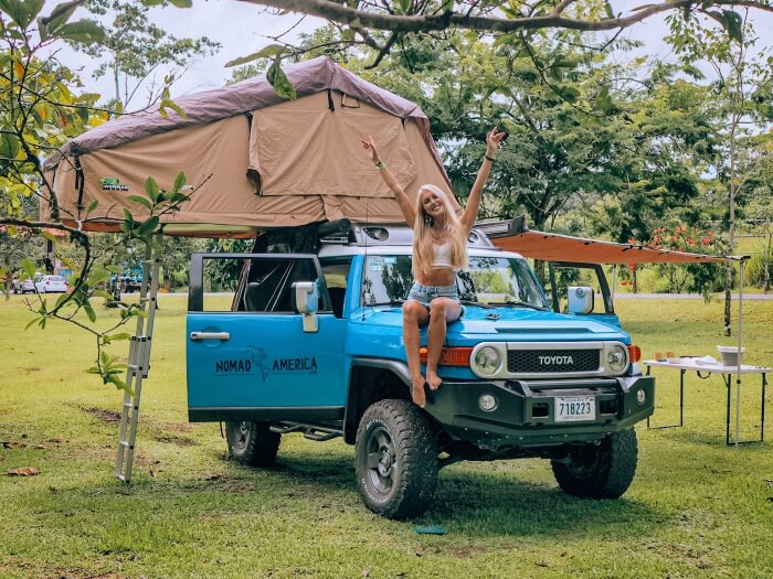 Me sitting on a blue 4x4 car with a beige rooftop tent, the perfect setup for a Costa Rica road trip