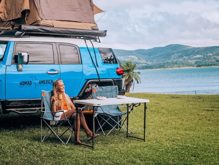 Me sitting on a camping chair, sipping morning coffee next to a lake at a campsite in Costa Rica