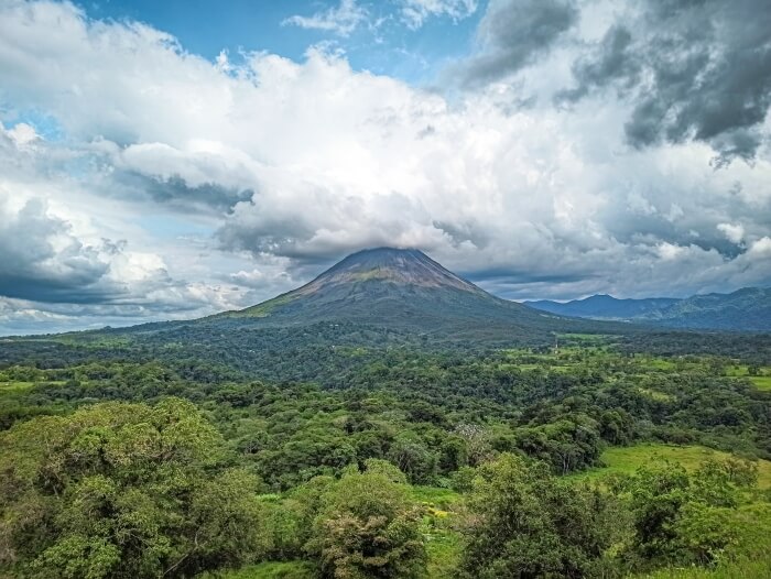 Arenal volcano surrounded by green vegetation and a dramatic cloudy sky in Costa Rica