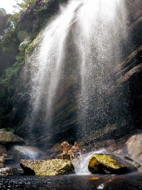 Two people sitting under Capivari waterfall in Chapada Diamantina, the best spot for hiking in Brazil