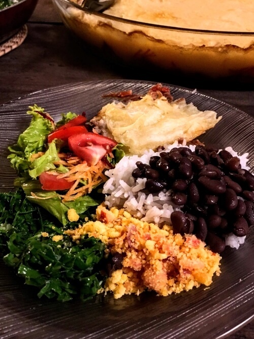 a plate full of classic Brazilian food such as rice, beans, farofa and escondidinho