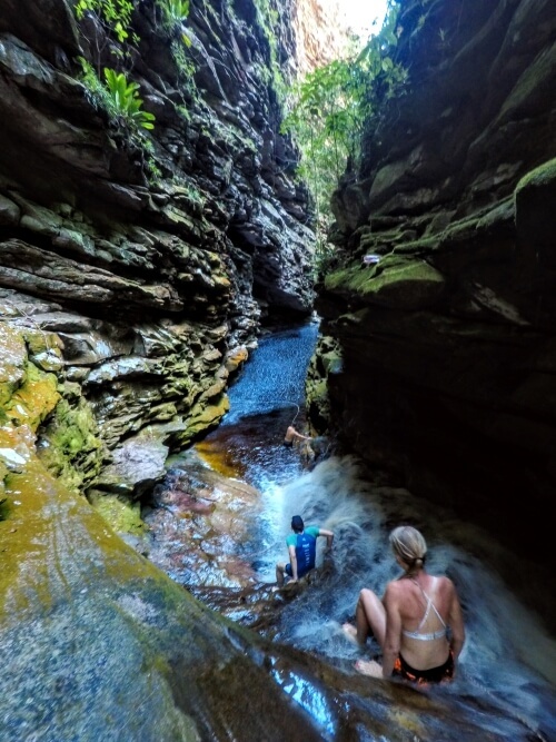 Hikers swimming through a river inside a narrow canyon in Brazil