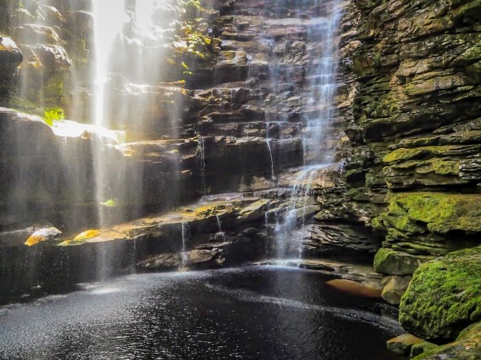 A rocky canyon with a waterfall and moss-covered walls in Chapada Diamantina, a top destination for hiking in Brazil