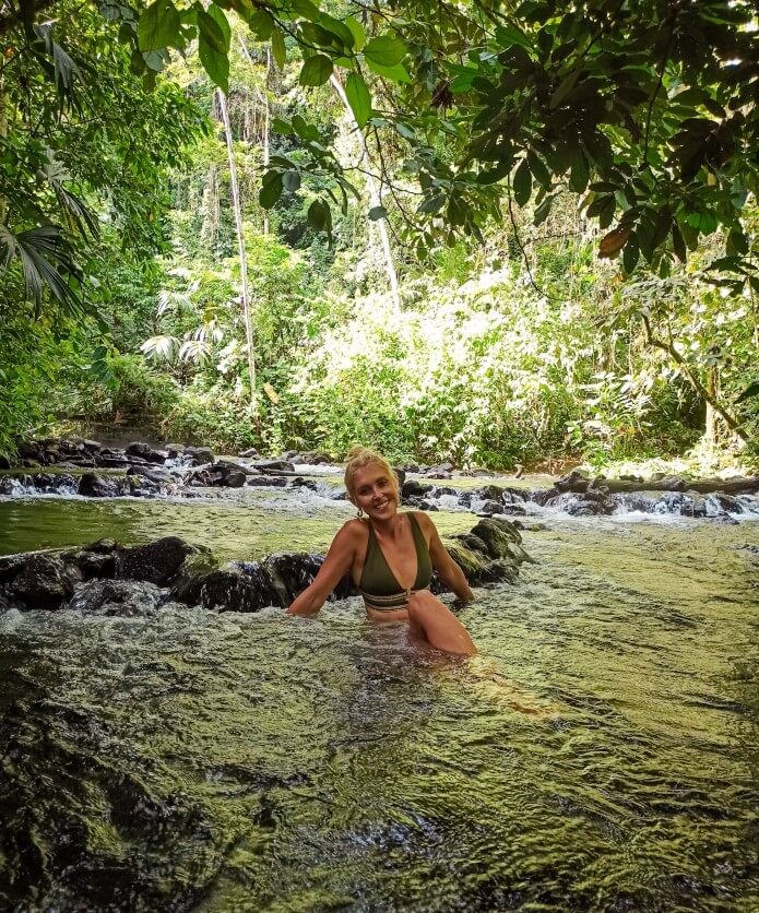 a girl sitting in the free natural hot springs of La Fortuna, one of the best things to include in your 10 day Costa Rica itinerary