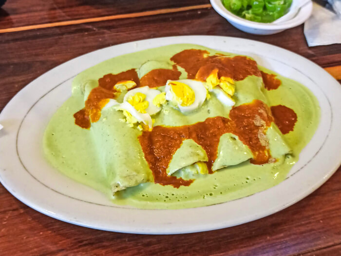A plate full of papadzules, a classic Yucatecan dish consisting of tortillas, egg and pumpkin seed sauce