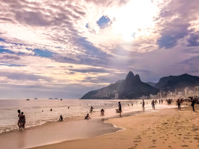 People swimming and sunbathing at the famous Ipanema beach in Rio; in the background there are the Two Brothers mountains.