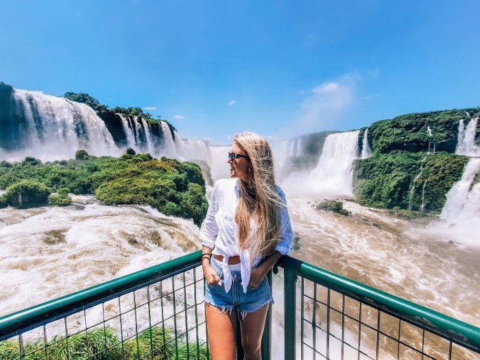 a woman standing in front of the Devil's Throat waterfall, the highlight of Iguazu Falls in Brazil