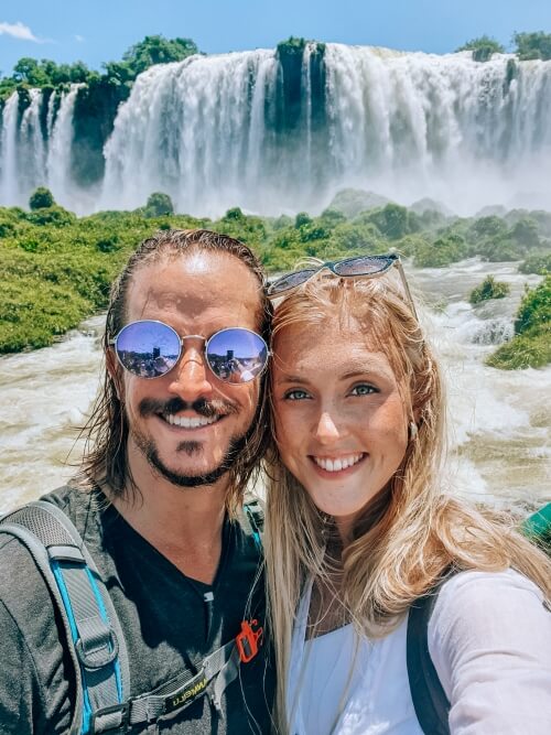 a couple posing in front of Iguacu falls in Brazil