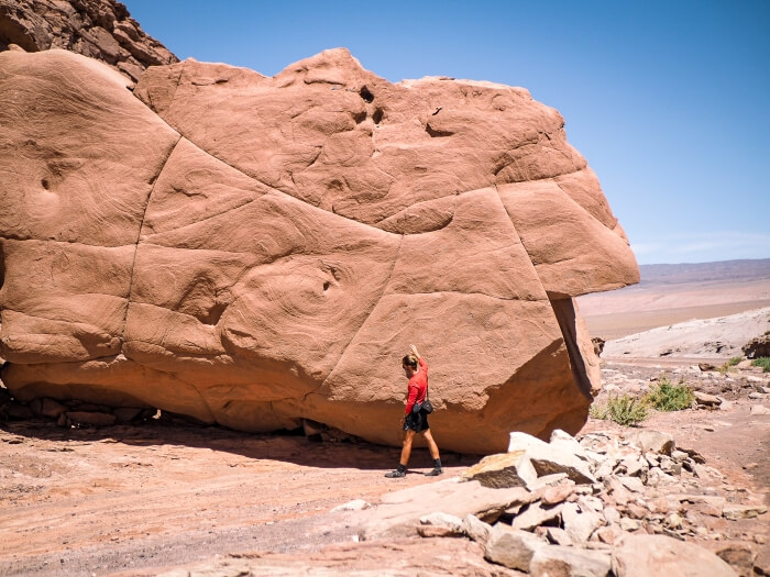 A man walking next to a huge orange rock called Piedra de la Coca near San Pedro de Atacama, Chile