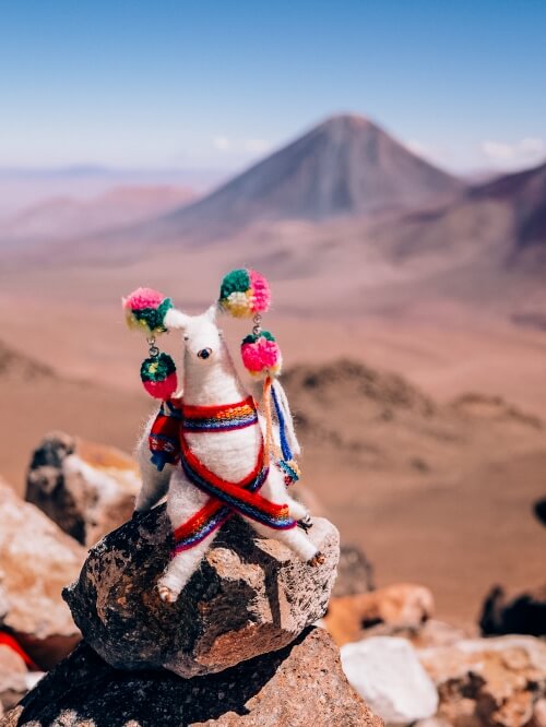 A handcrafted toy vicuna with a backdrop of Licancabur Volcano viewed from Cerro Toco hiking trail