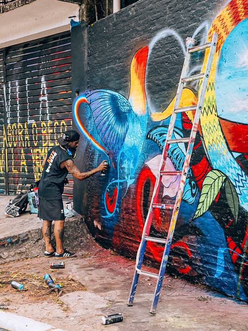 a street artist creating a mural at Beco do Batman