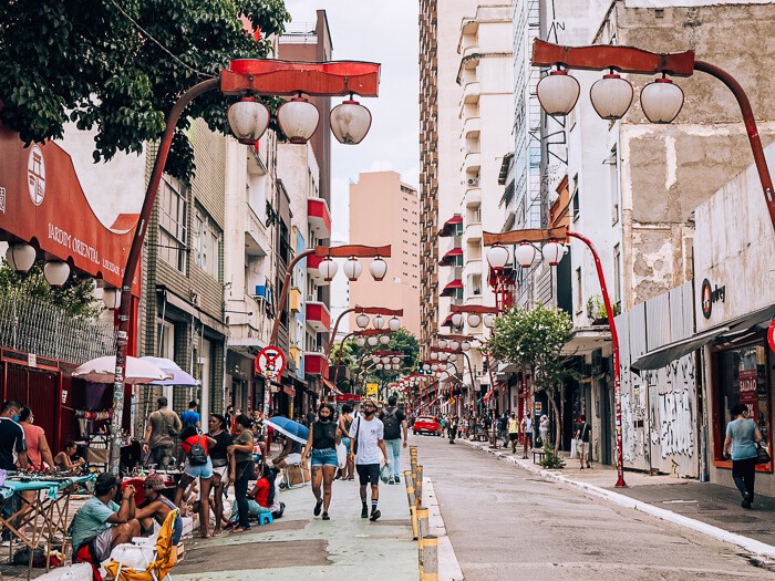 Pedestrians walking on a street lined with oriental lanterns in the Liberdade neighborhood aka the Japantown of Sao Paulo, Brazil.