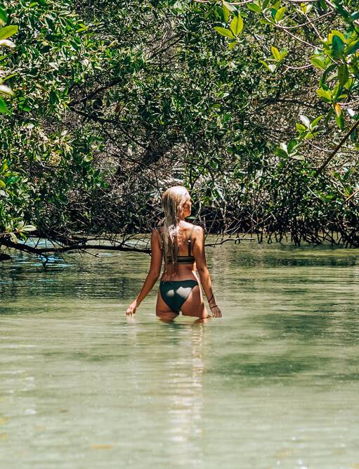 a girl standing in water surrounded by mangroves at El Estero