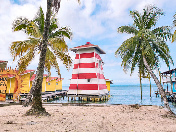 Two palm trees in front of a red and white house built on stilts on Carenero Island in Panama.