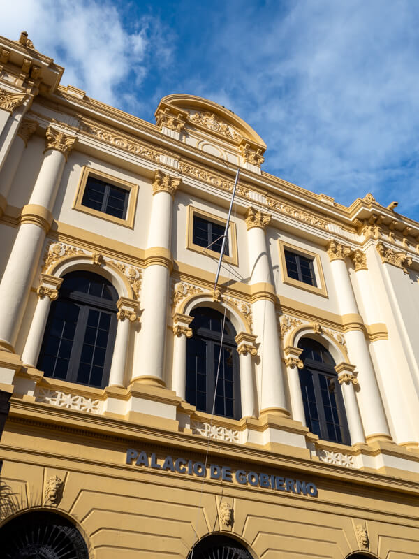 The facade of a yellow Spanish colonial style building with intricate carvings.