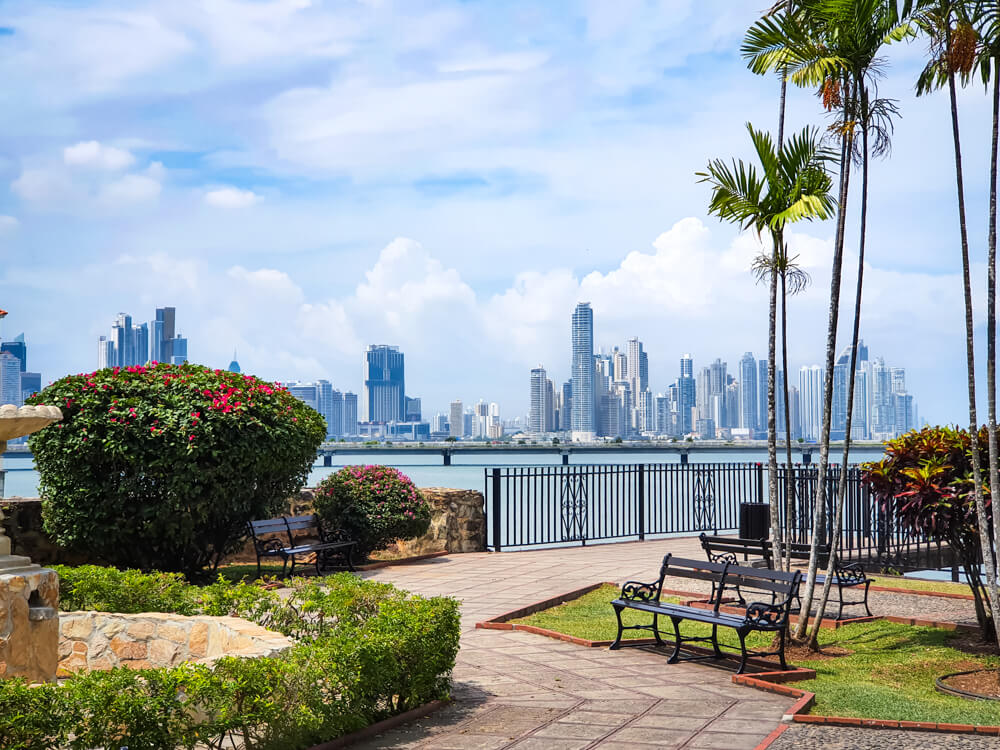 A small seafront park in Casco Viejo, with a view of the modern skyline of Panama City in the background.