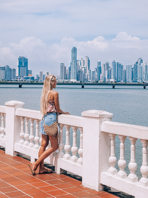 a girl leaning on a railing and admiring the view of Panama City skyline in Casco Viejo