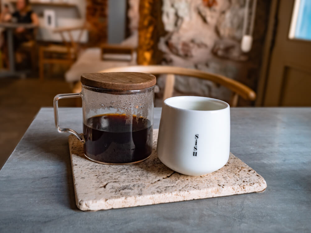 A small glass jug with Geisha coffee and a white mug at Sisu Coffee Studio.