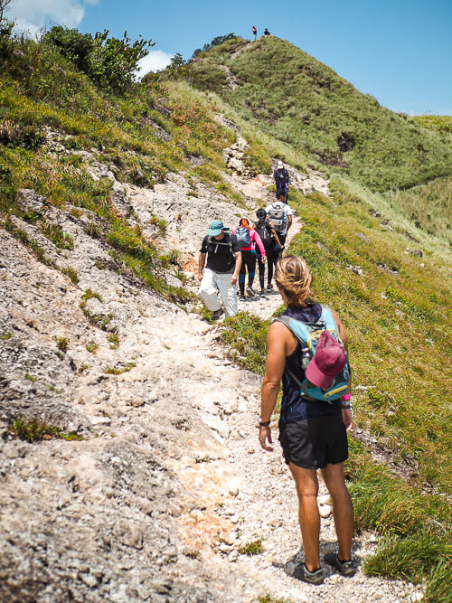 a group of hikers walking on a narrow trail among steep green hills in Panama