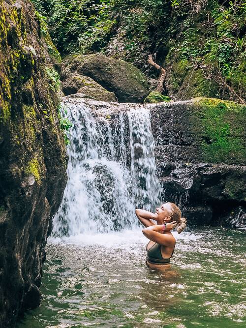 a girl taking a dip in a waterfall at La India Dormida hike in Anton Valley