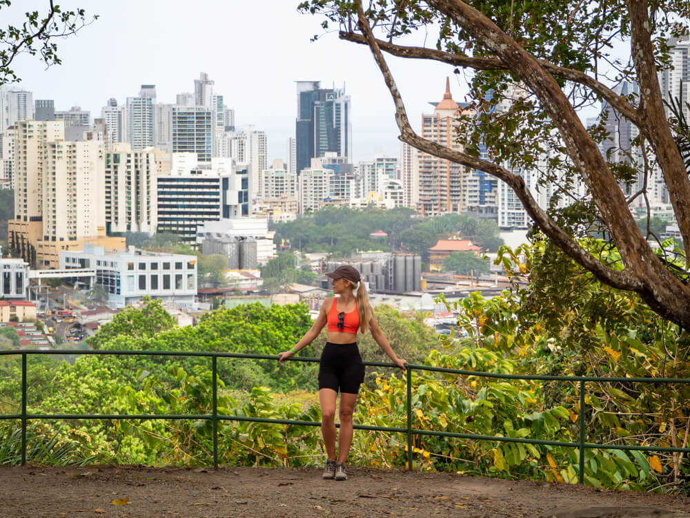 Me leaning on a railing in the Metropolitan Natural Park of Panama City, with the city's skyline in the background.