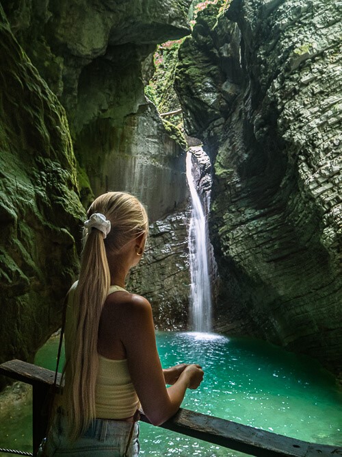 a woman admiring the breathtaking Slap Kozjak Waterfall and its emerald green pool